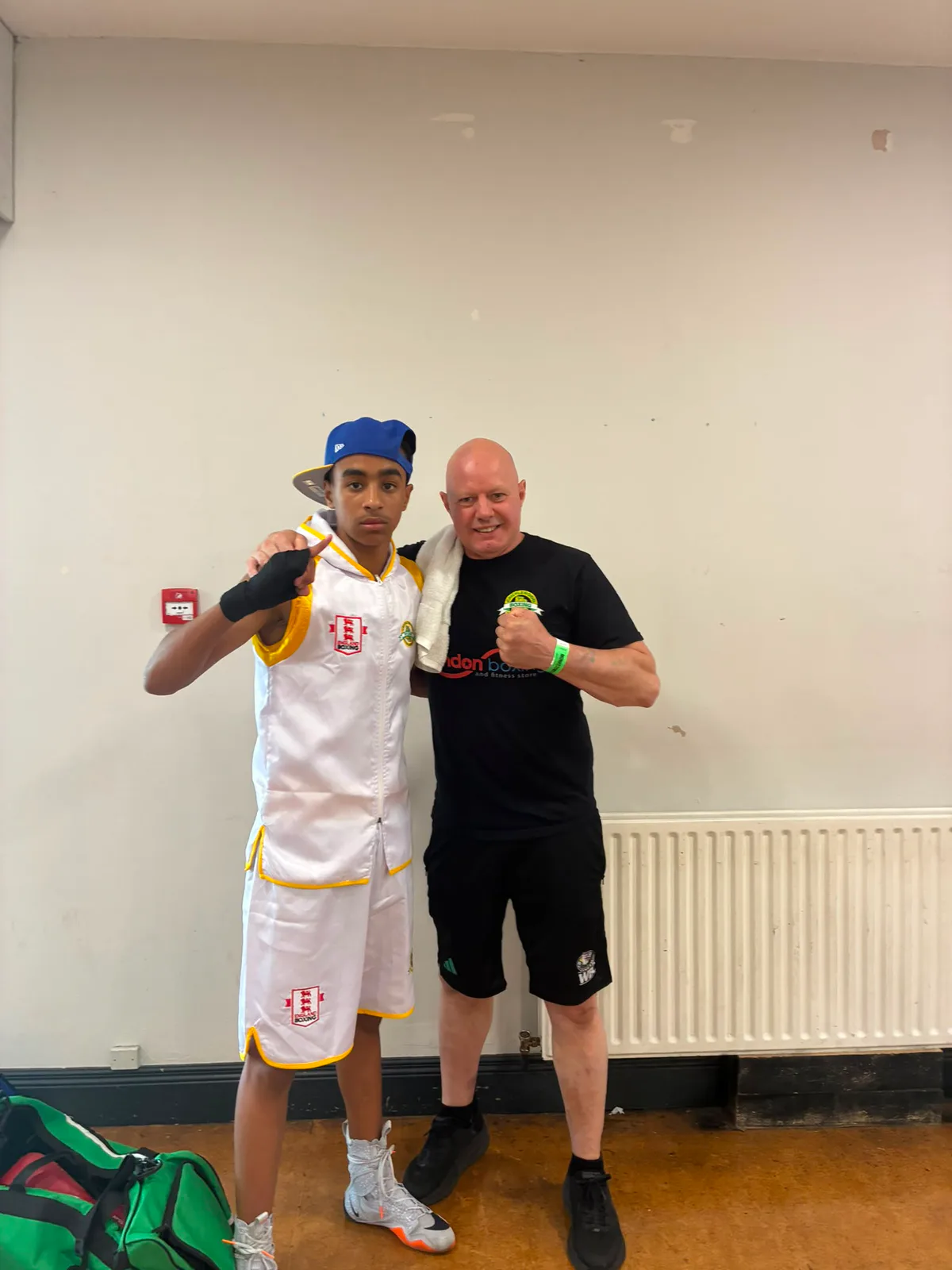 A young boxer in Cricklewood colours with his coach before a bout