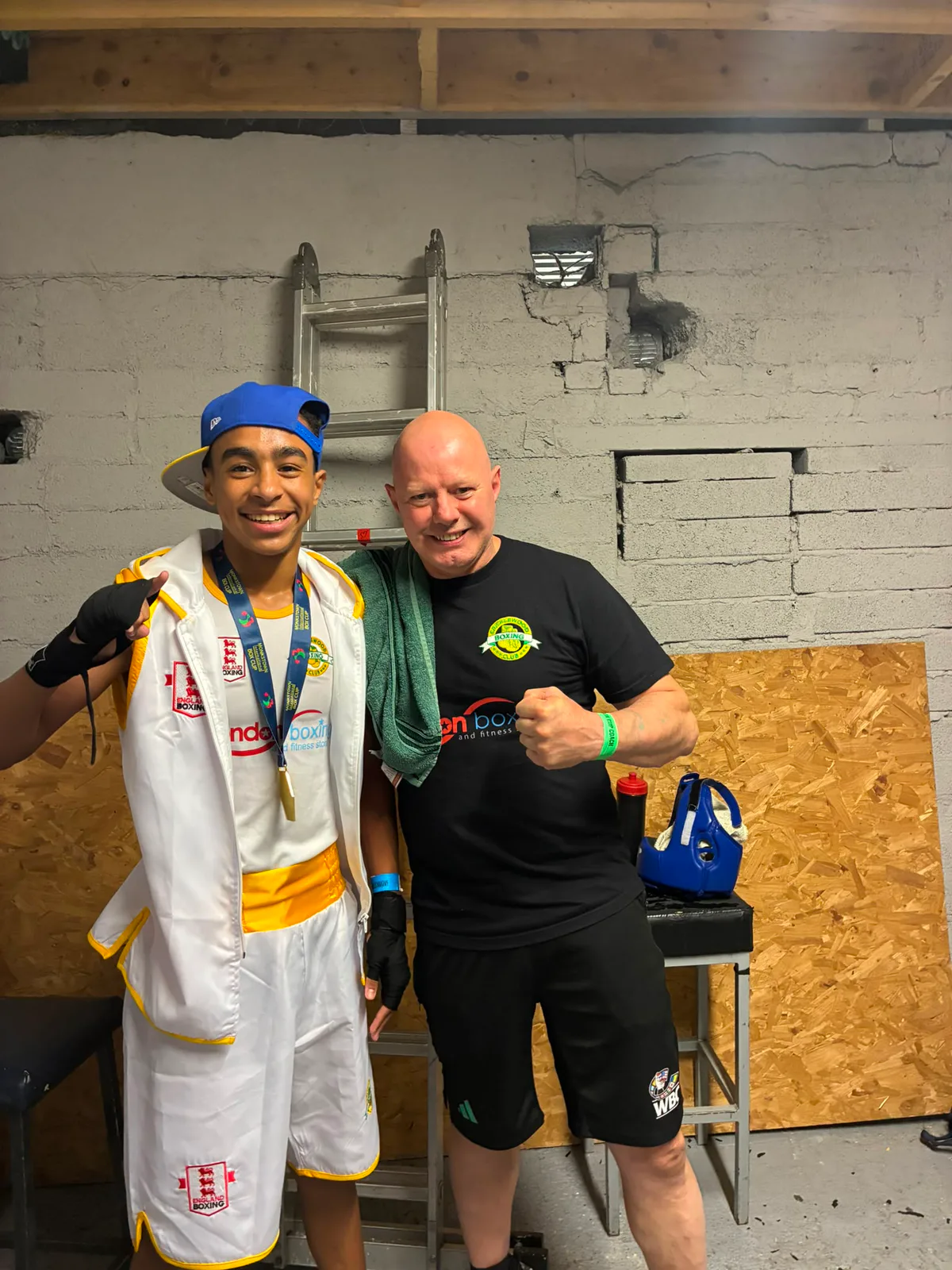 A medal-winning young boxer smiling with his coach