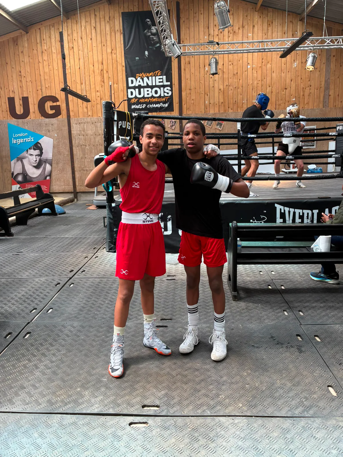 Two young boxers standing together beside a boxing ring